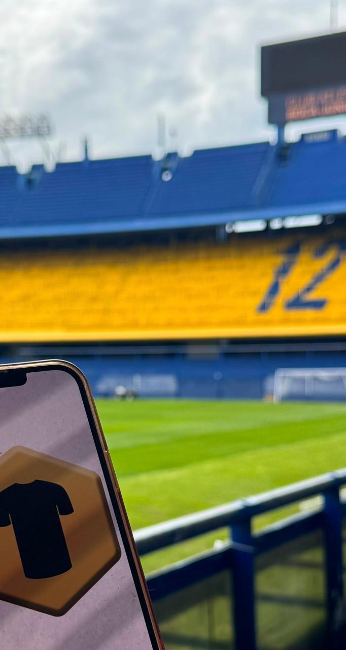The TEAM-VP emblem displayed on a phone overlooking a football stadium